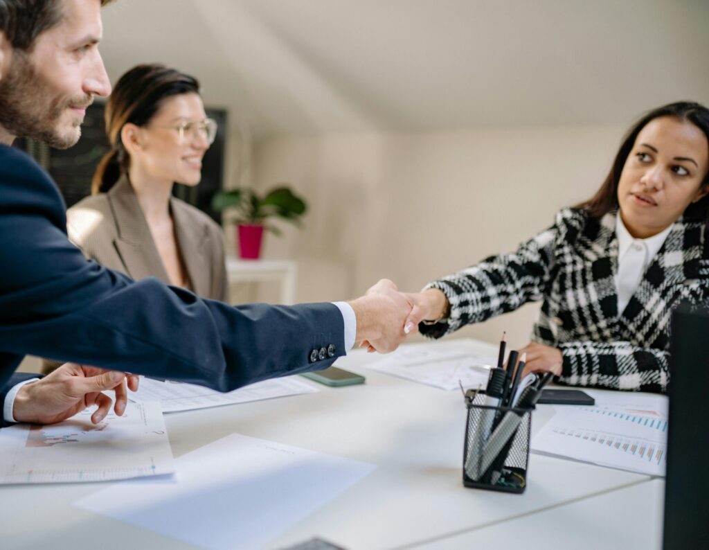 A group of diverse professionals engaged in a business meeting and handshake in a modern office.